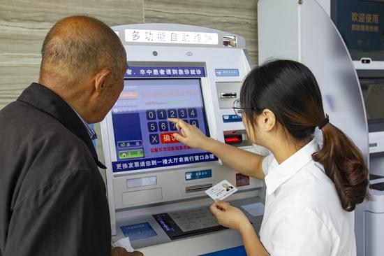 服務(wù)人員通過掛號自助機(jī)為老人預(yù)約專家。潘迎霞 攝